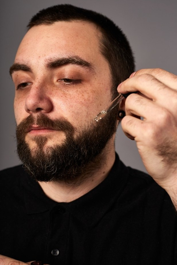 applicerar skäggolja med droppar från pipett